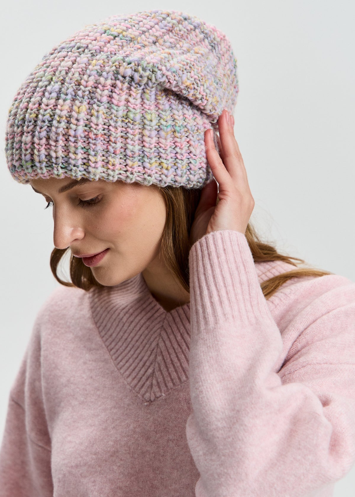 BRIKOLY London Unicorn pastel multicolor knit beanie worn by a model looking down and touching the brim.