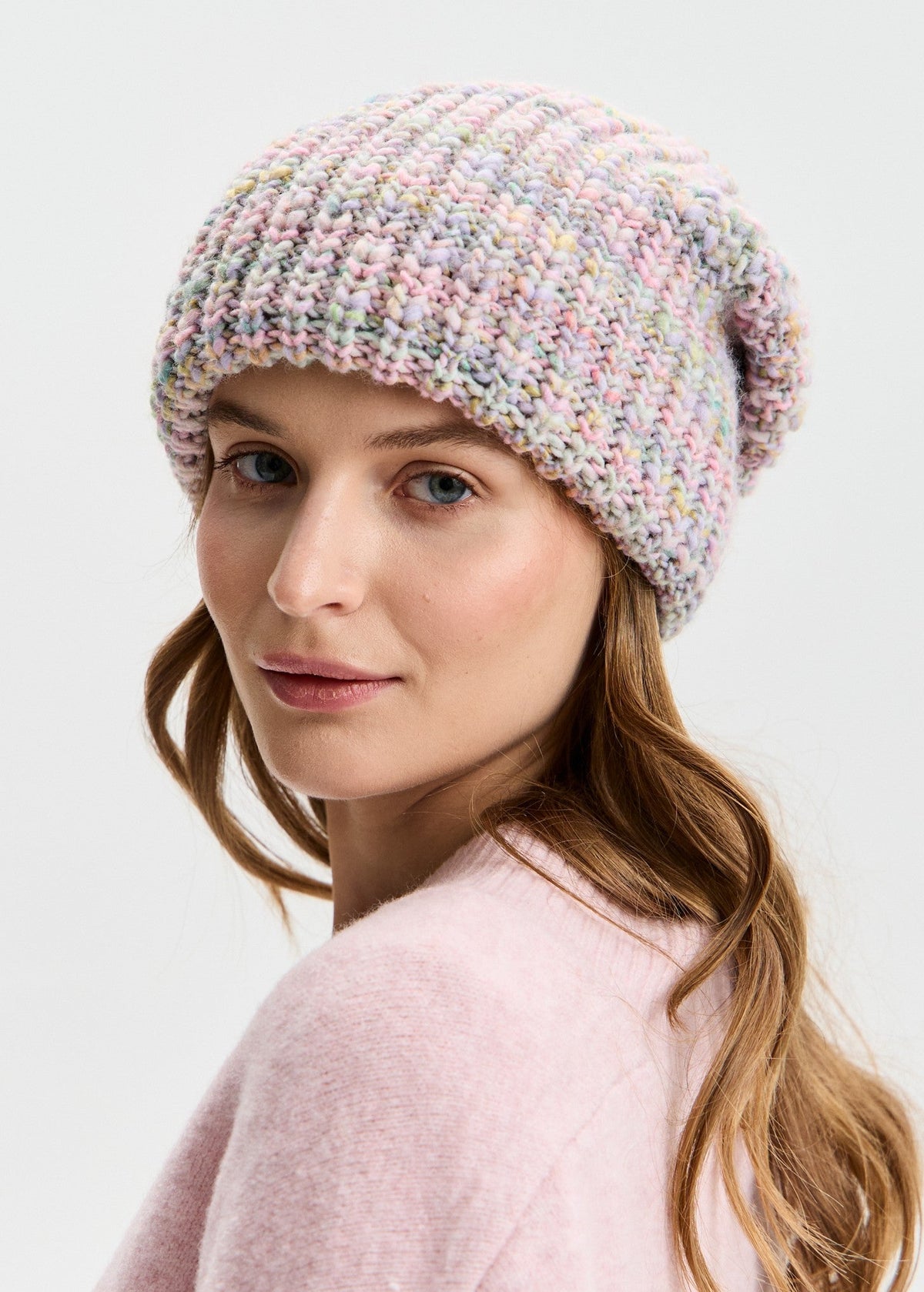 BRIKOLY London Unicorn pastel multicolor knit beanie shown on a model looking back toward the camera.