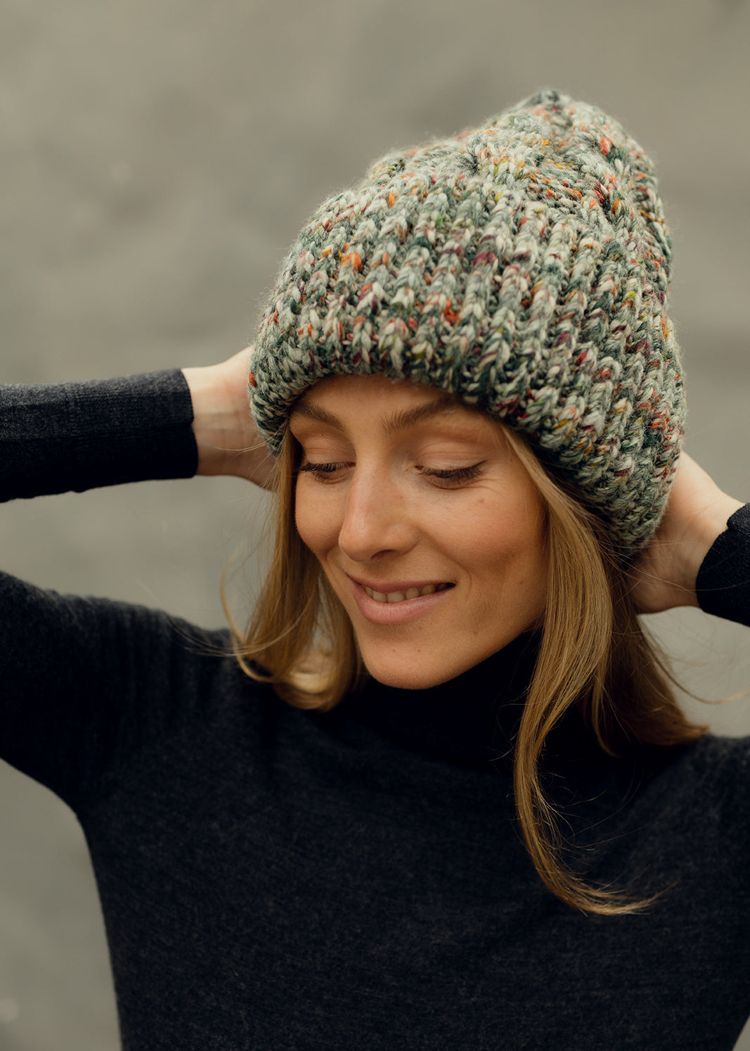 Tokyo Green cable knit wool beanie: Three-quarter portrait with hands behind the head