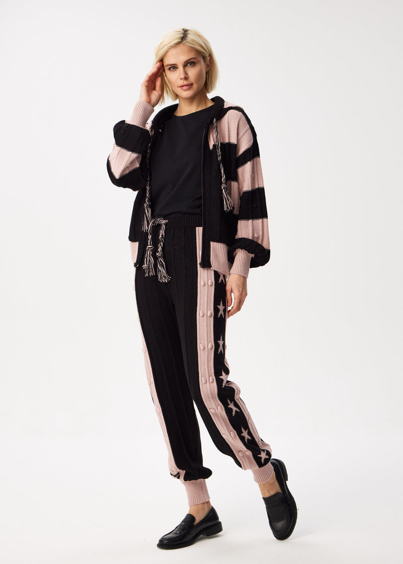 Woman wearing a black and pink outfit with a sheer jacket on a white background