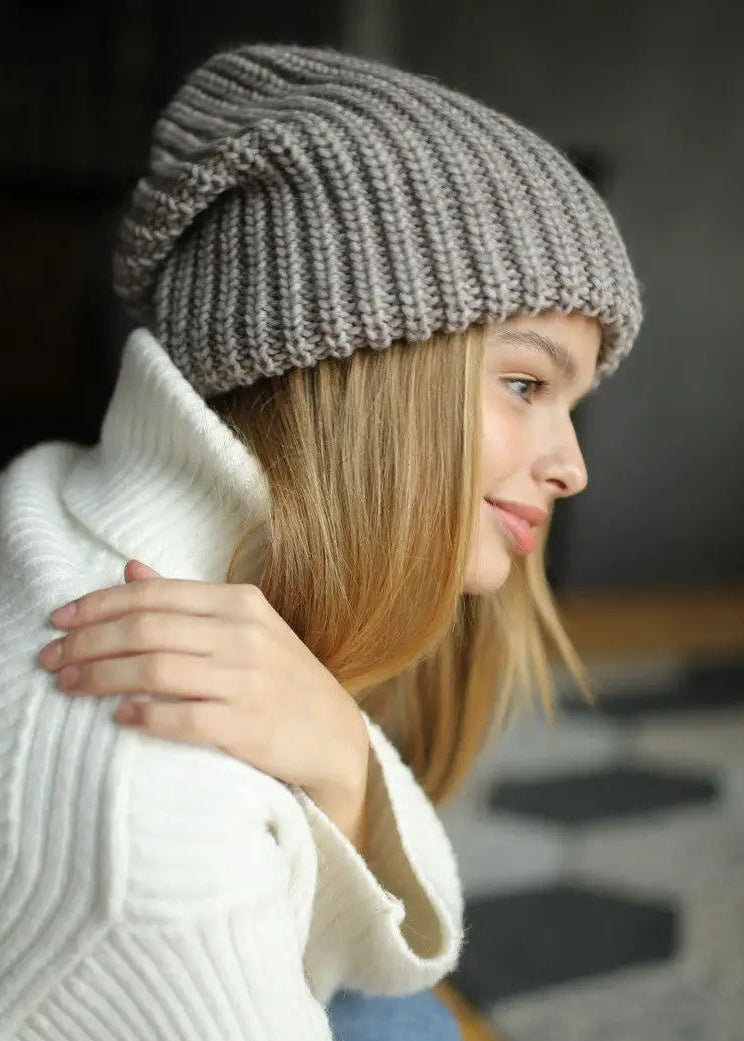 BRIKOLY London Gray & Beige knit beanie shown close up on a model in a white sweater.
