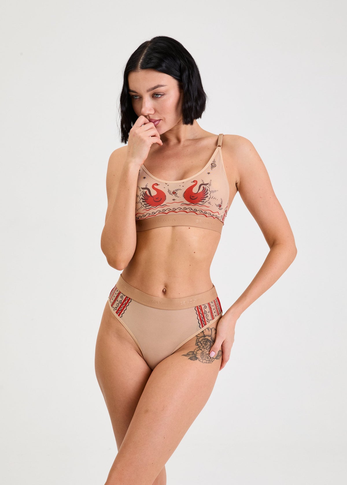 Woman wearing a beige bikini with red and gold accents on a white background