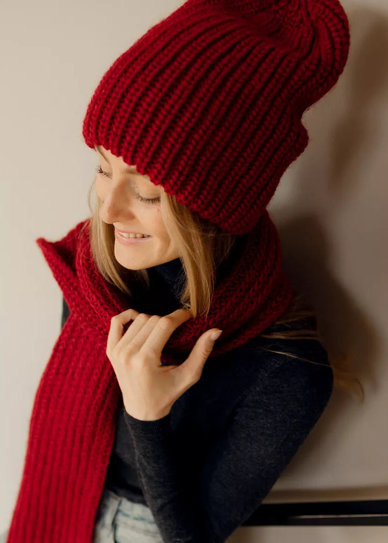 BRIKOLY London Burgundy knit beanie shown on a model looking down with a matching scarf.