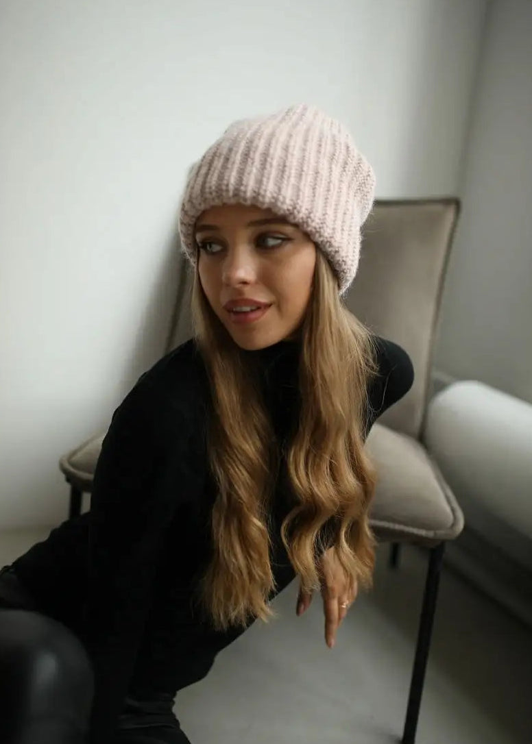 BRIKOLY London Pink knit beanie shown on a seated model near a window.