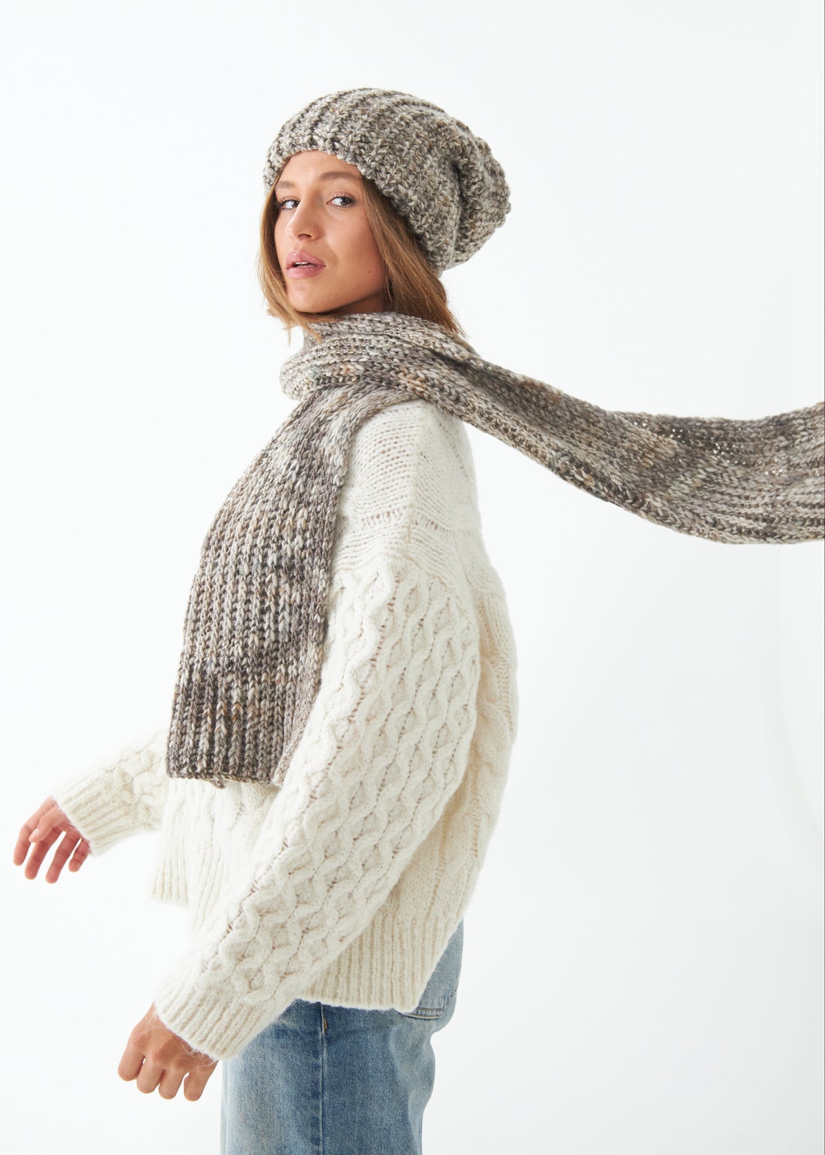 Oversized Gray alpaca-wool scarf: Side outfit view with one end held outward; beanie sold separately