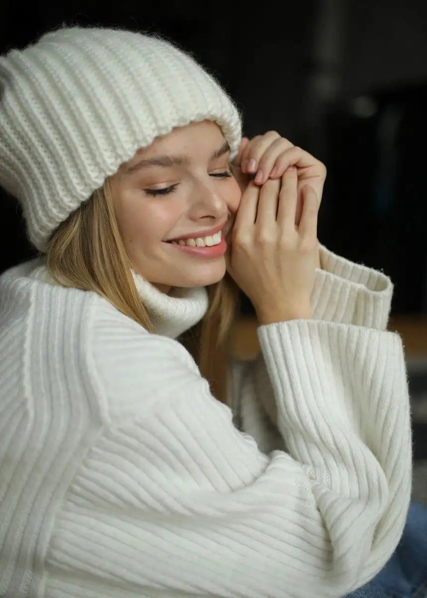 BRIKOLY London White knit beanie worn by a smiling model touching the side.