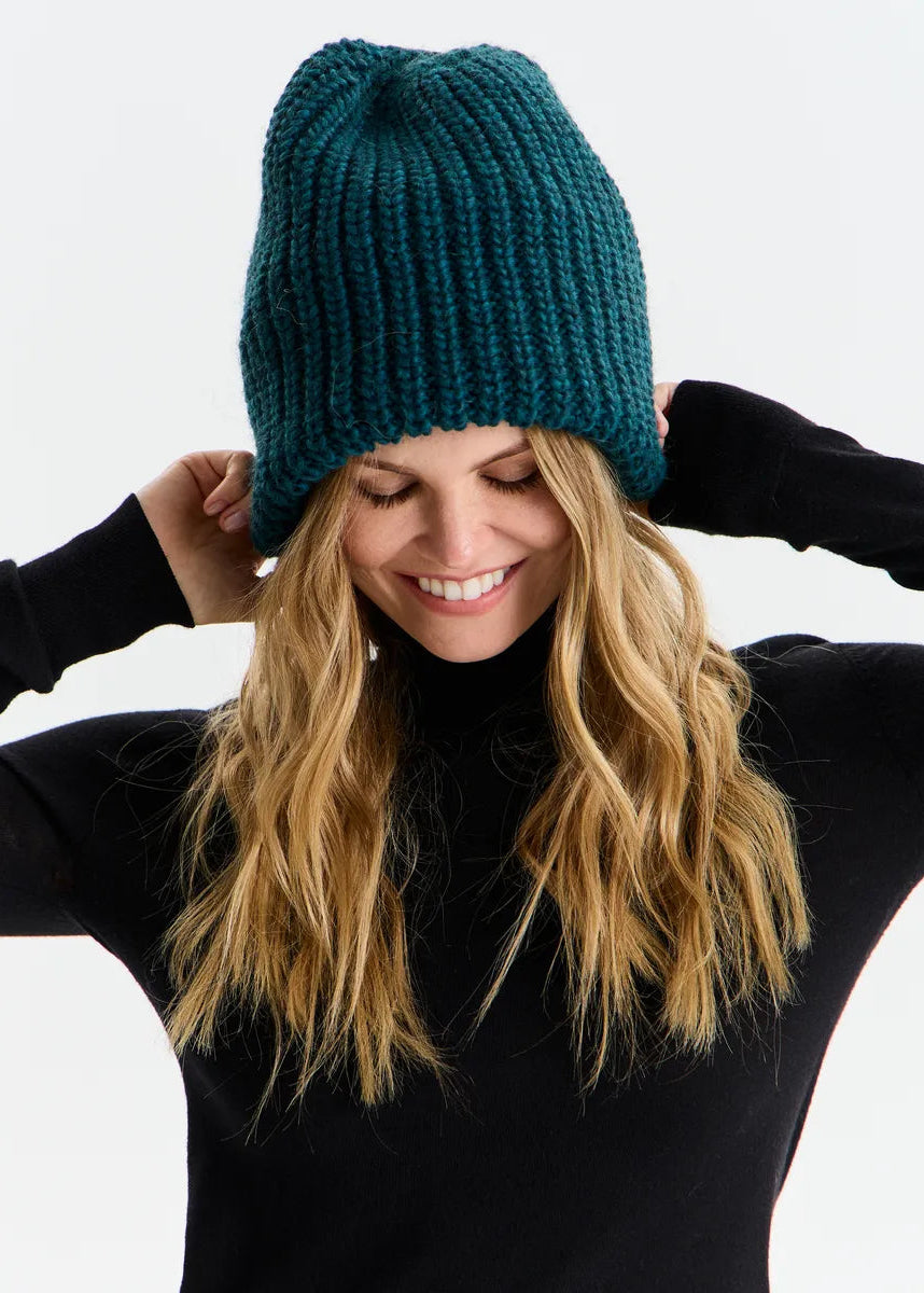 BRIKOLY London Emerald knit beanie worn by a model adjusting the sides.