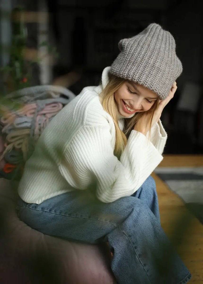 BRIKOLY London Gray & Beige knit beanie worn by a seated model looking down.