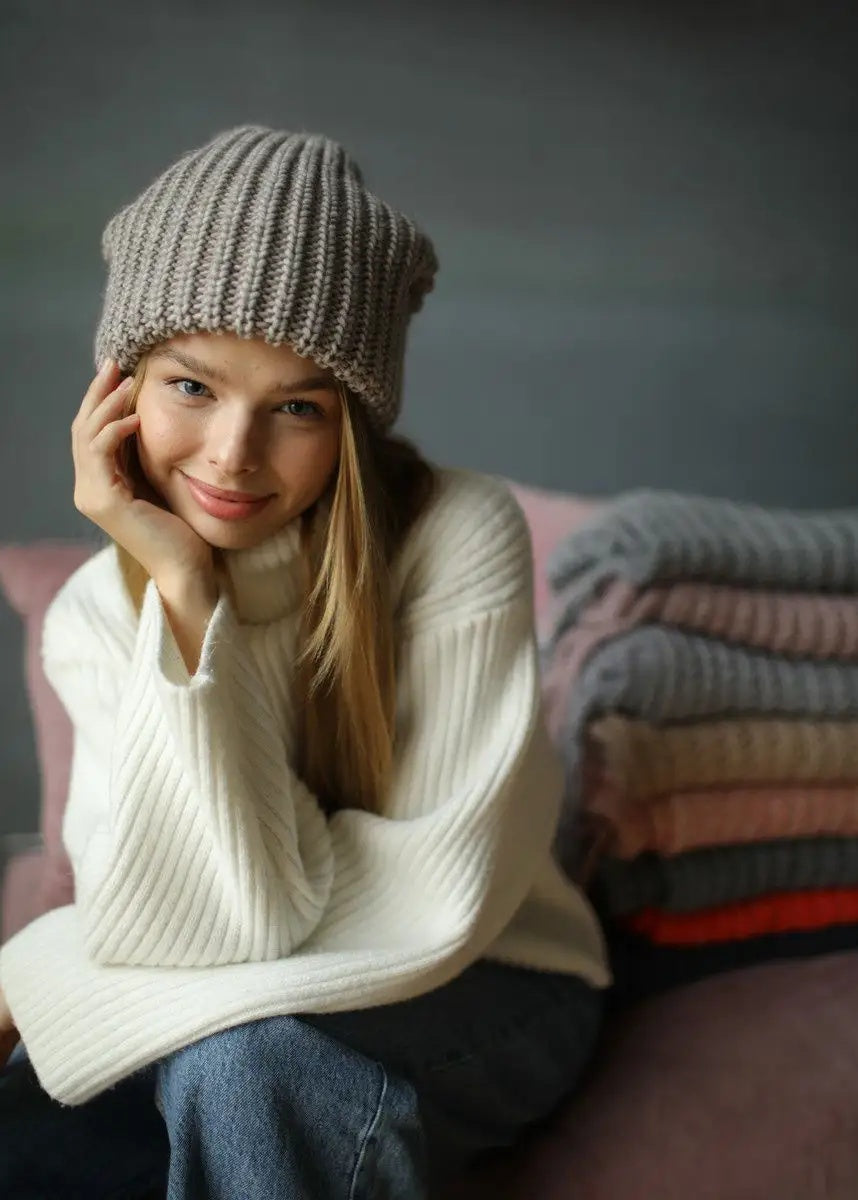 BRIKOLY London Gray & Beige knit beanie shown on a seated model touching the side.