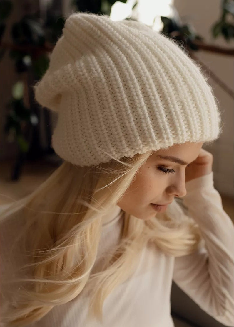 BRIKOLY London White knit beanie shown close up on a model looking down.