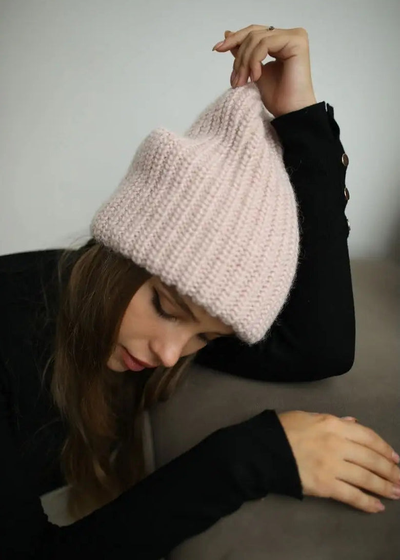 BRIKOLY London Pink knit beanie worn by a model holding the crown.