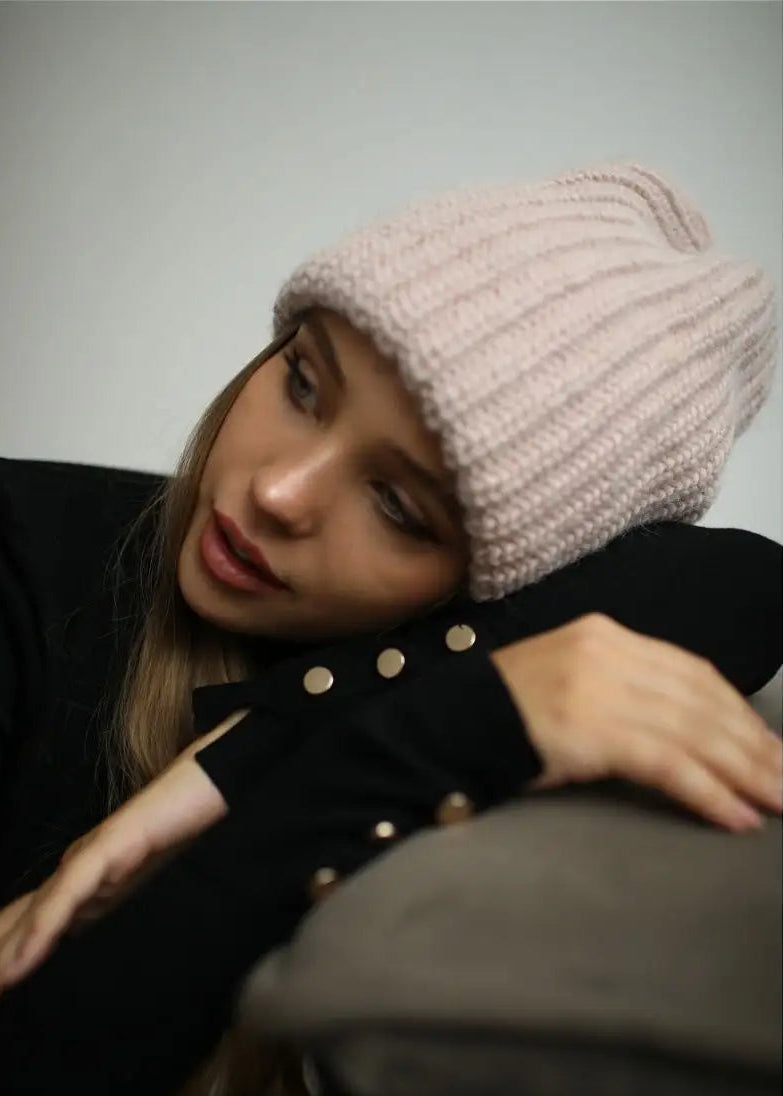 BRIKOLY London Pink knit beanie shown on a model resting her head on her arm.