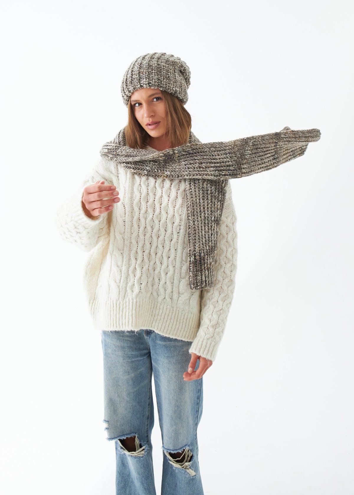 Oversized Gray alpaca-wool scarf: Full outfit view holding a scarf end outward; beanie sold separately