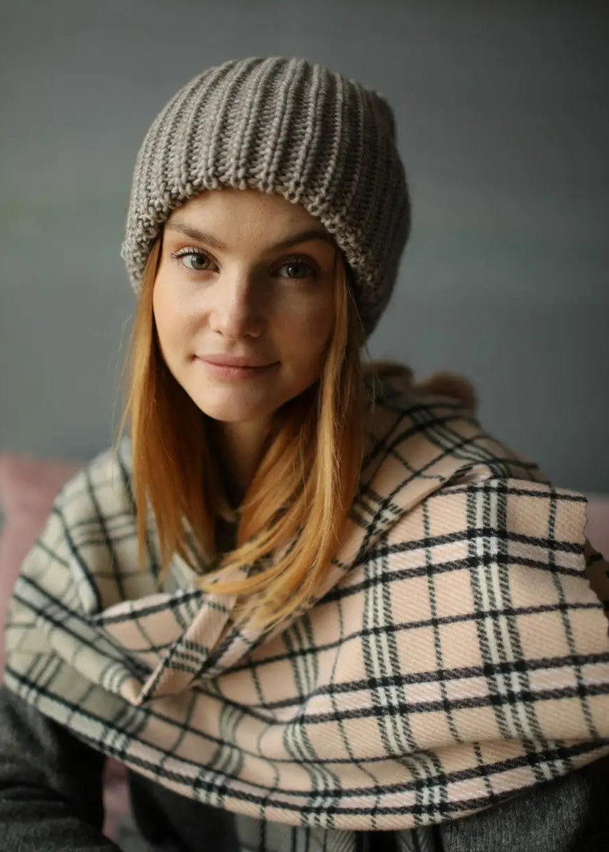 BRIKOLY London Gray & Beige knit beanie shown close up with a plaid blanket.