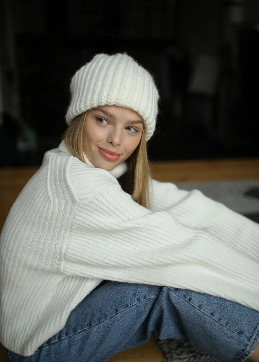 BRIKOLY London White knit beanie shown on a seated model looking to the side.