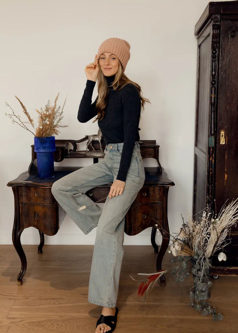 BRIKOLY London Peach knit beanie shown on a seated model in a full outfit.