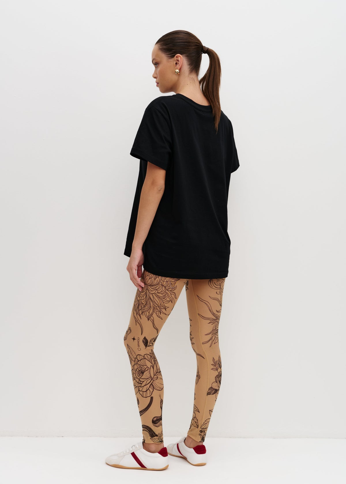 Person wearing a black t-shirt and patterned leggings on a white background