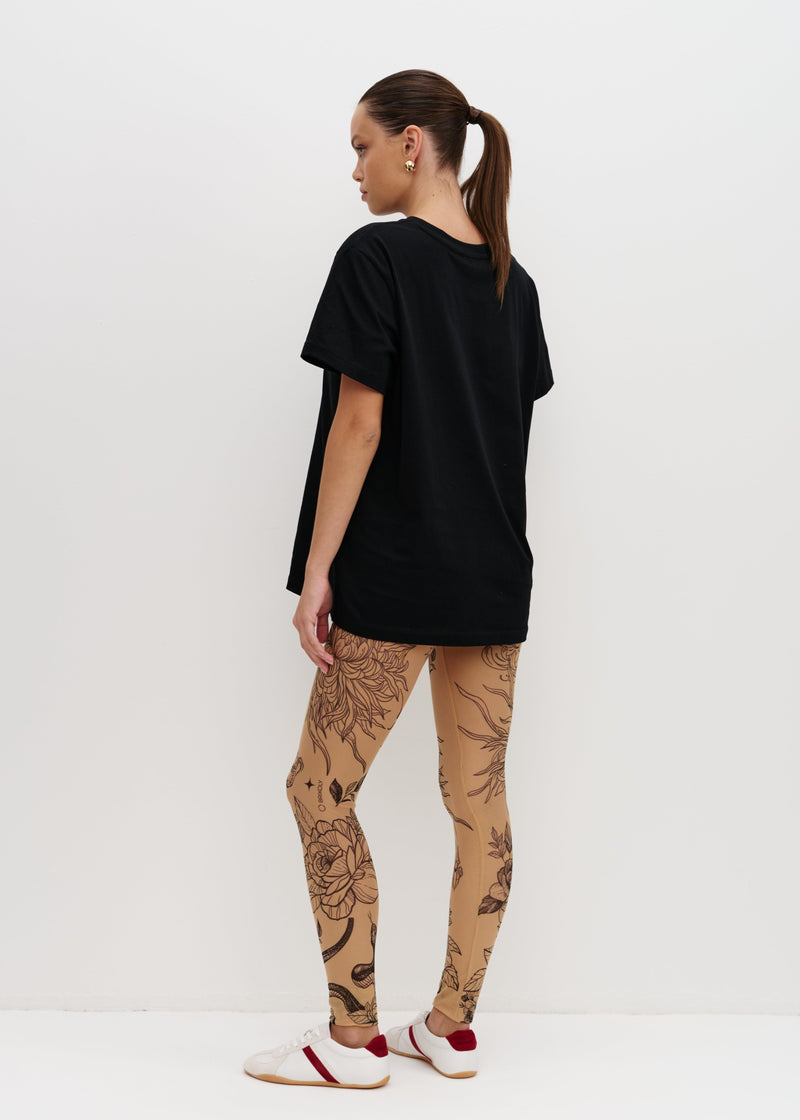 Person wearing a black t-shirt and patterned leggings on a white background
