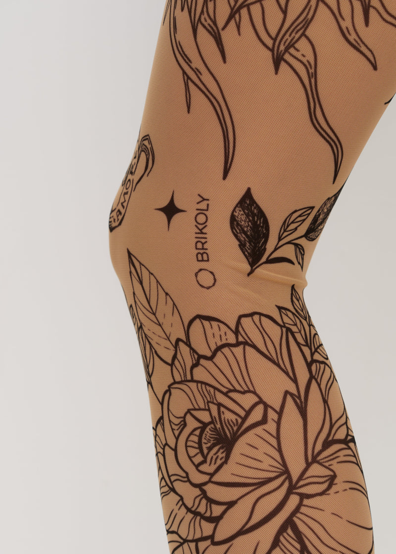 Tan leggings with black floral and tribal designs on a beige background.
