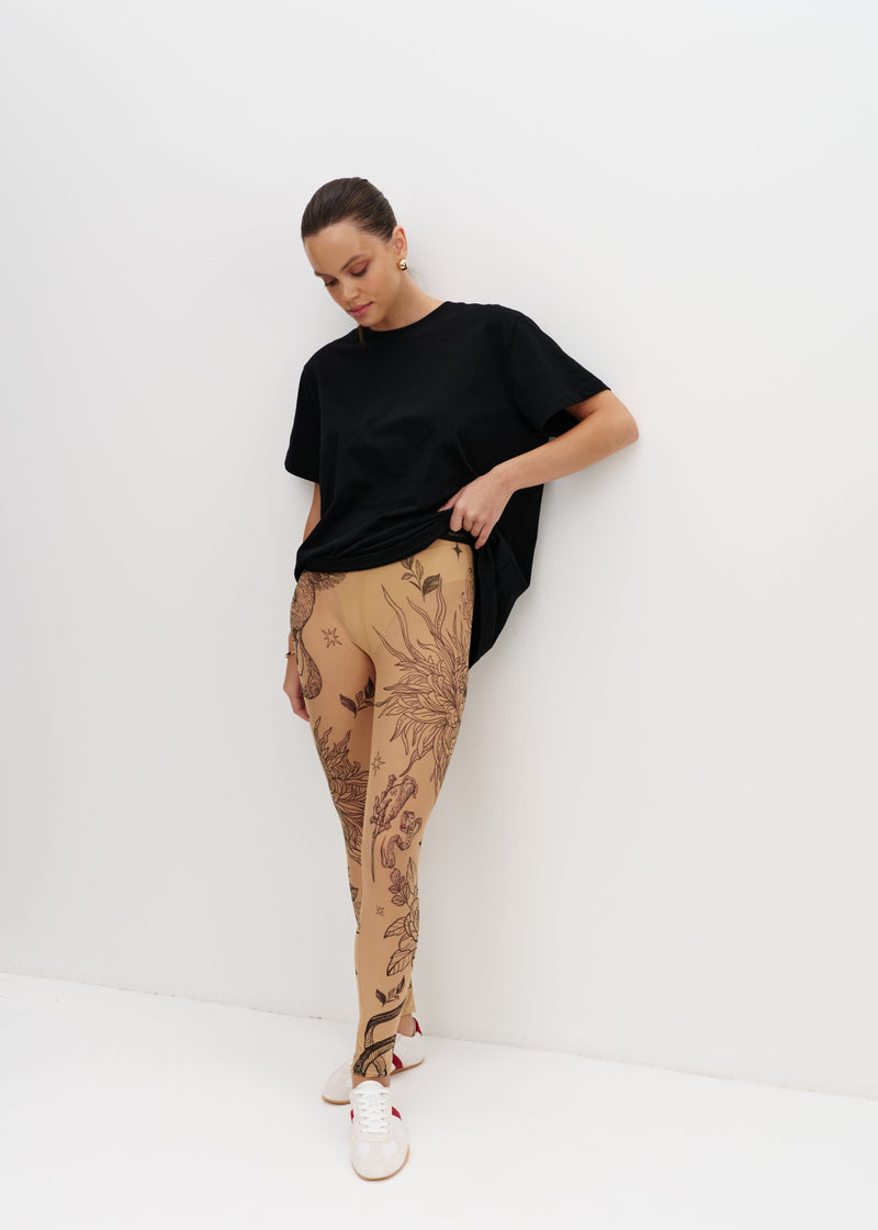 Person wearing a black t-shirt and beige pants with a pattern on a white background