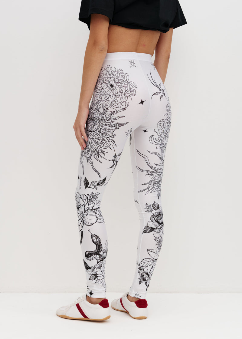 White leggings with black floral patterns worn by a person on a white background