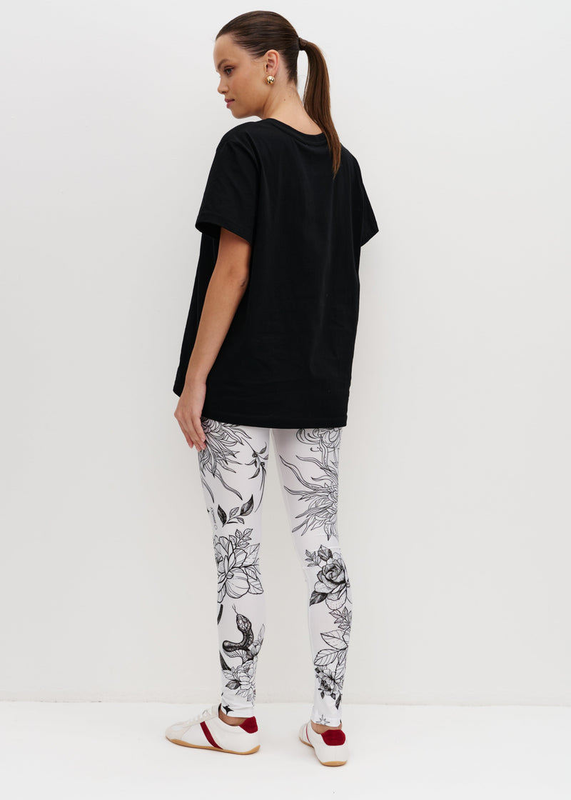 Person wearing a black t-shirt and white pants with black floral pattern on a white background