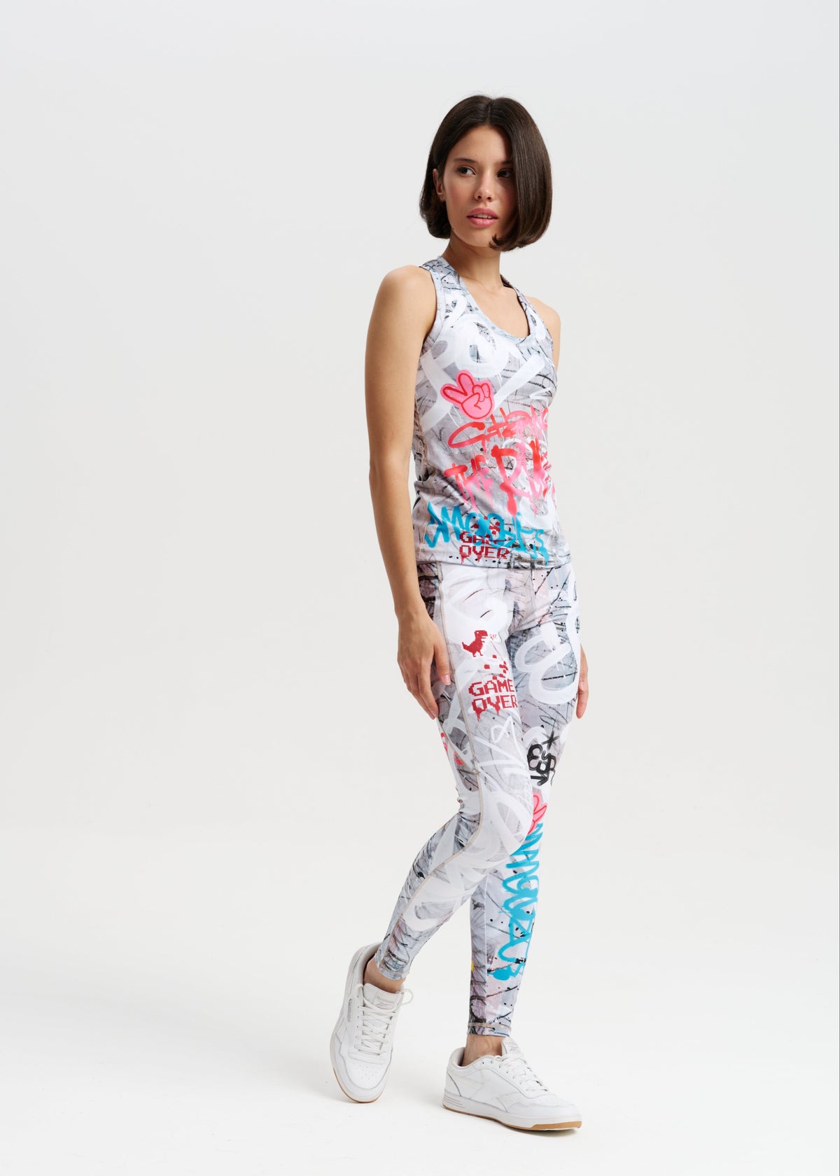 Woman wearing a sleeveless top and pants with colorful abstract designs on a white background