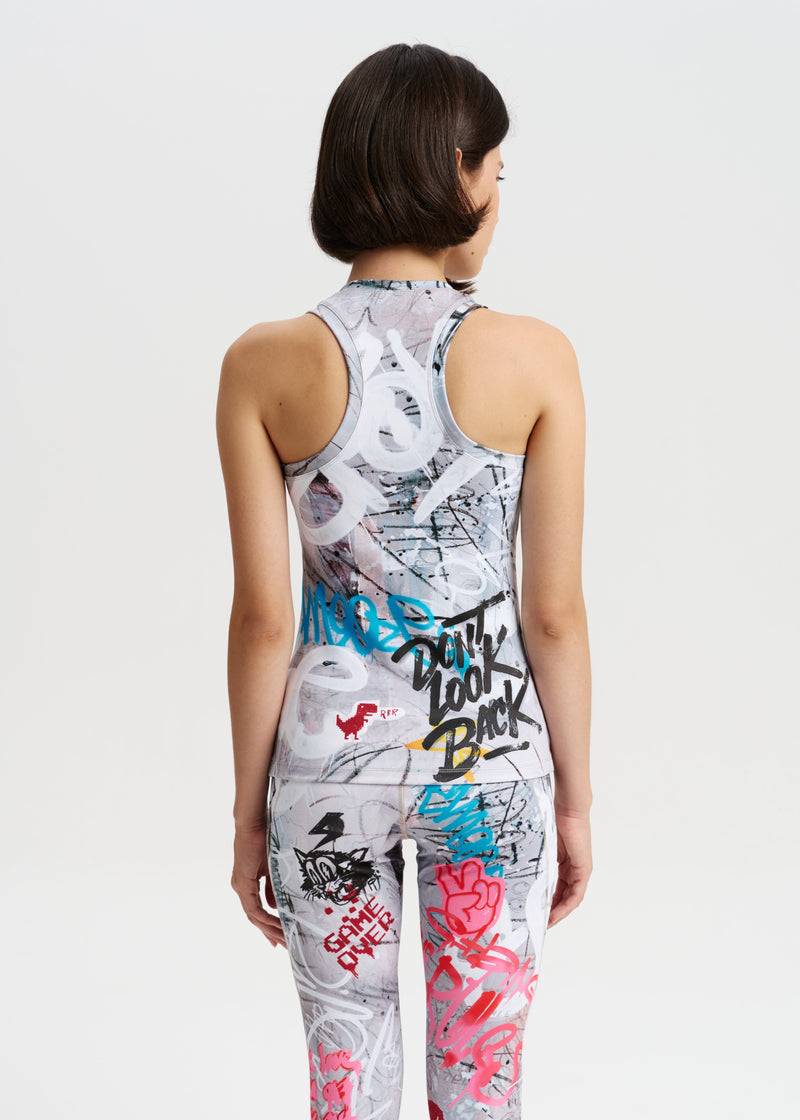 Person wearing a sleeveless top and pants with graffiti-style designs on a plain background
