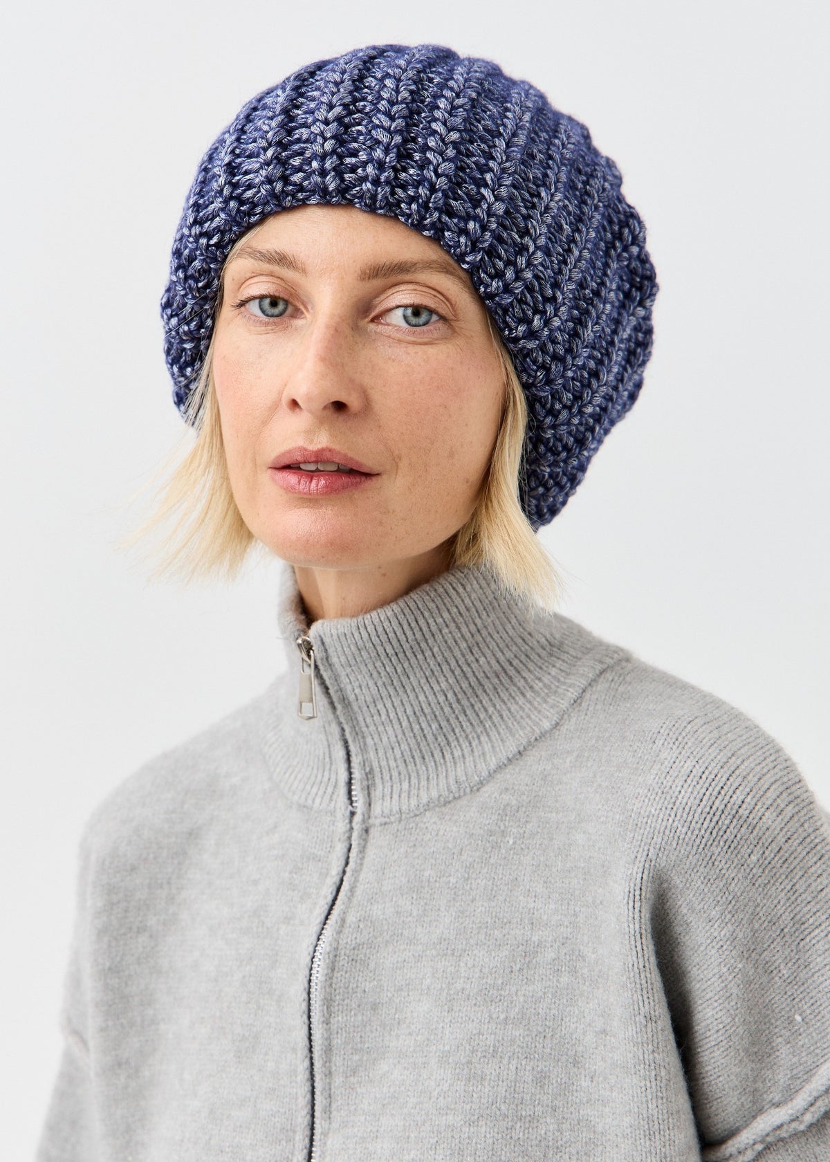 BRIKOLY Lustre Denim Melange oversized knit beanie shown in a front view on a model.