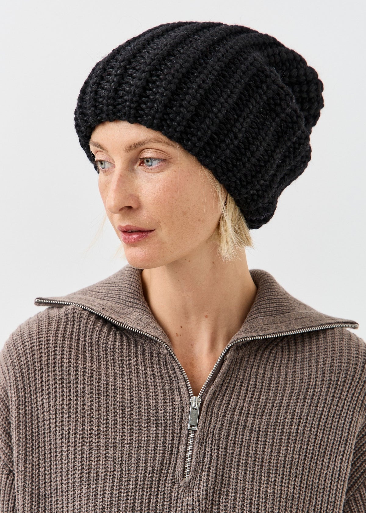 BRIKOLY Lustre Black Melange oversized knit beanie shown on a model looking to the side.