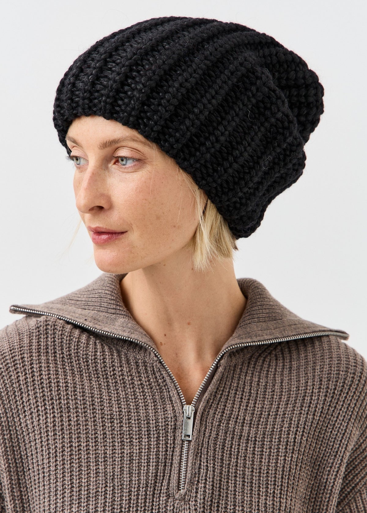 BRIKOLY Lustre Black Melange oversized knit beanie shown on a model looking down.