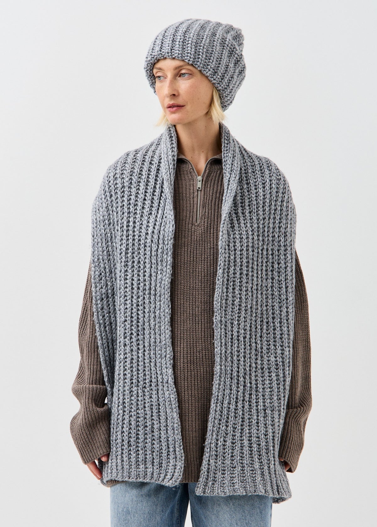 BRIKOLY Lustre Gray Melange knit scarf draped down the front of a model with both ends visible.