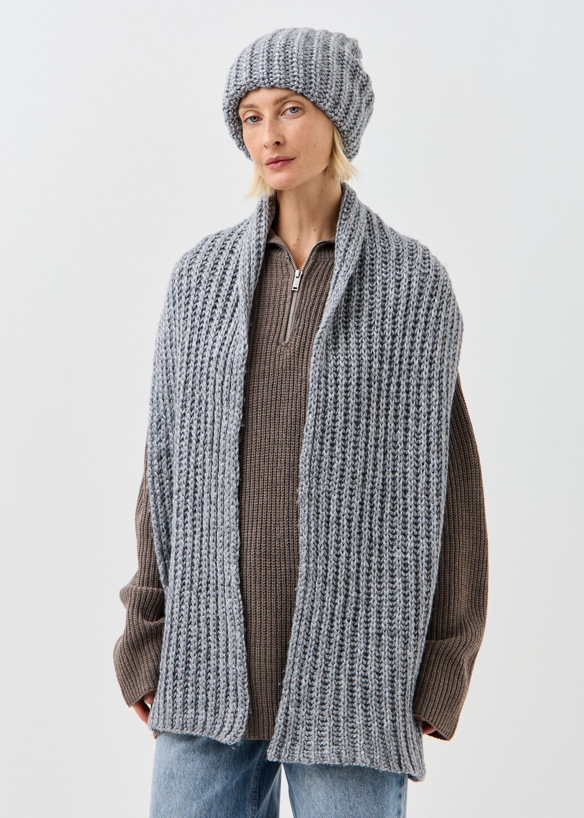 BRIKOLY Lustre Gray Melange knit scarf shown draped over a model's shoulders with a matching hat.