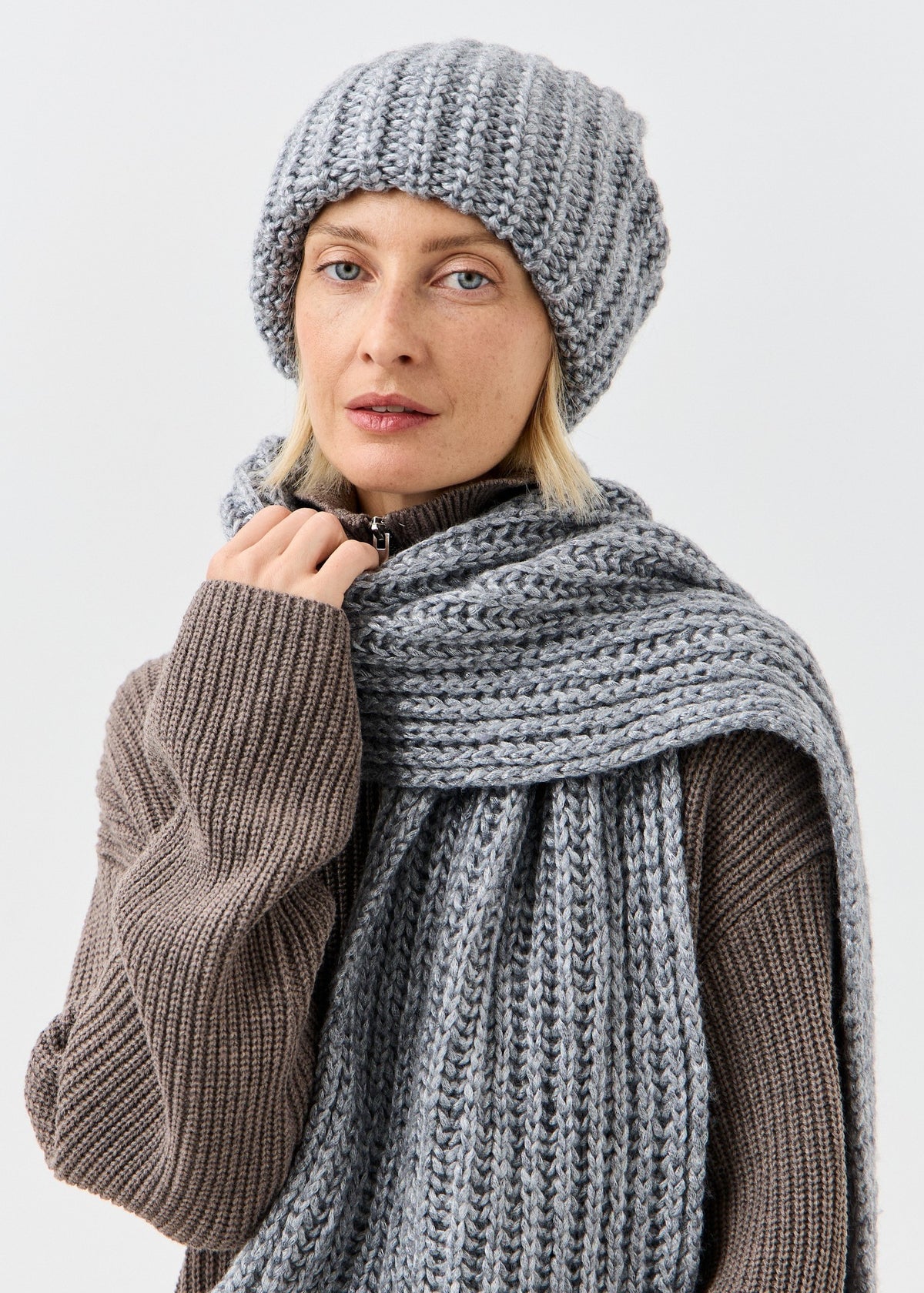 BRIKOLY Lustre Gray Melange knit scarf worn by a model holding the scarf near the collar.