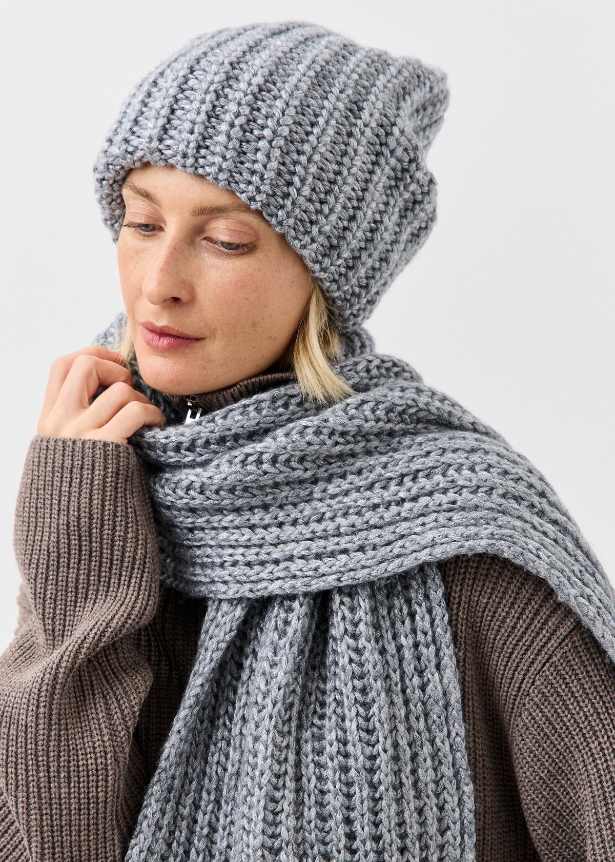 BRIKOLY Lustre Gray Melange knit scarf worn by a model looking down.