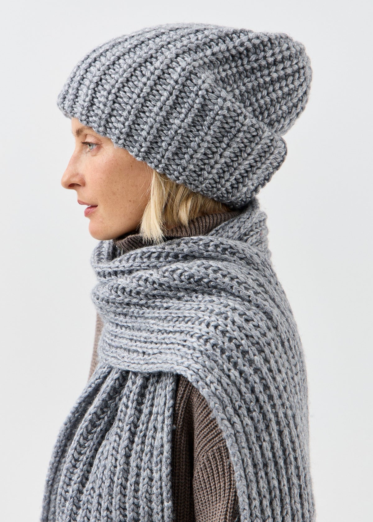 BRIKOLY Lustre Gray Melange knit scarf shown in a side view wrapped around a model's shoulders.