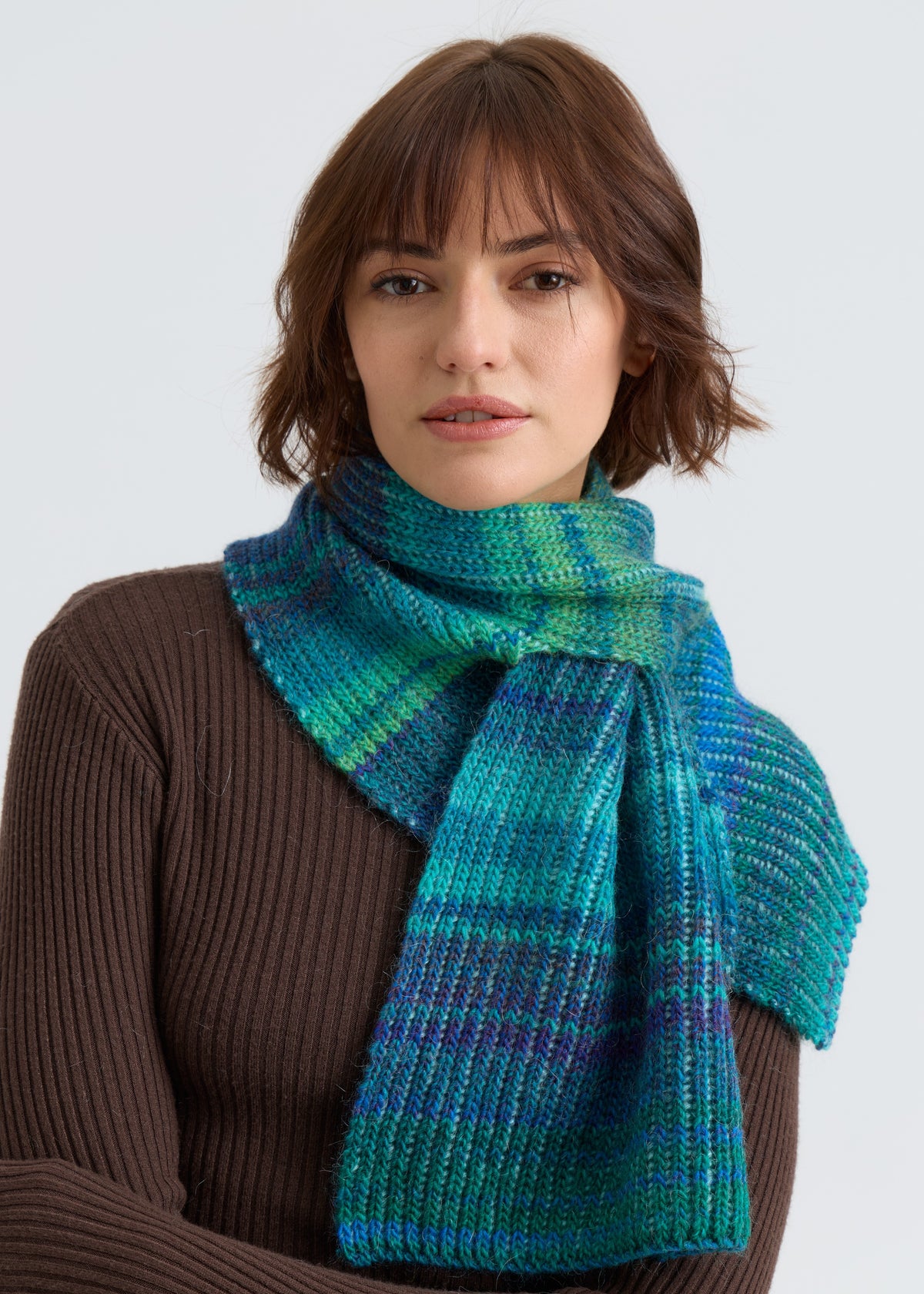 Woman wearing a blue plaid scarf against a white background