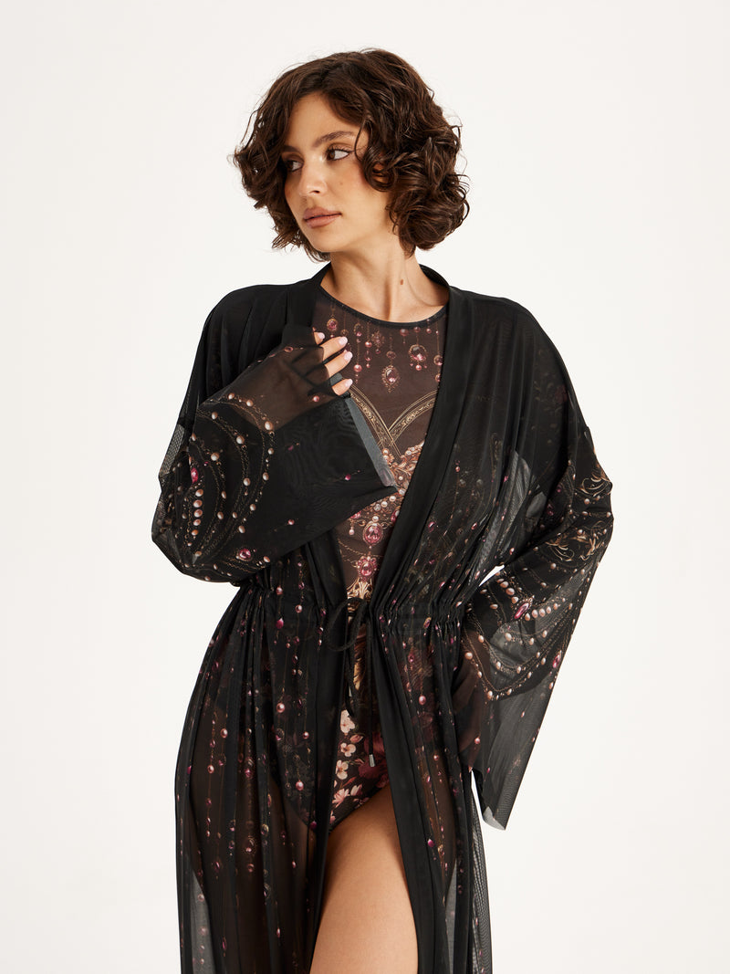 Woman wearing a black floral beach dress with a matching smart swimsuit SPF50 on a white background