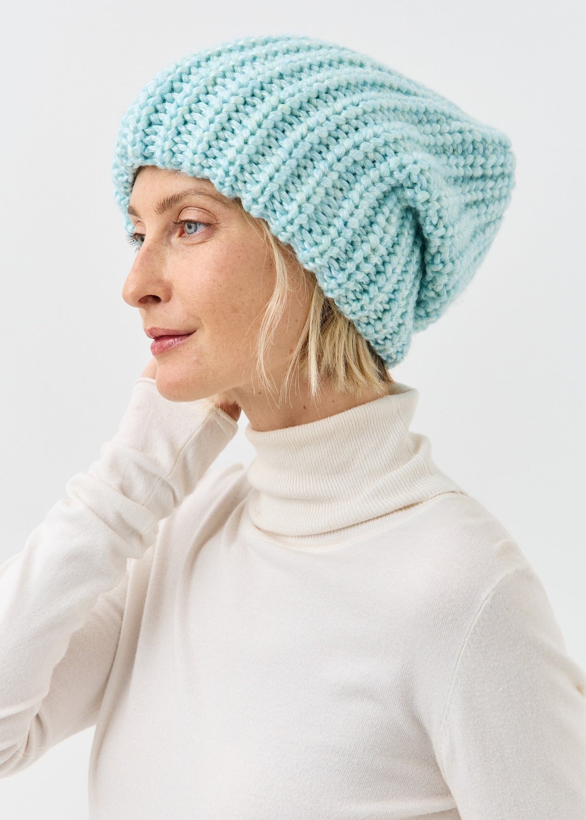 Lustre Blue Melange ribbed beanie worn with a white turtleneck
