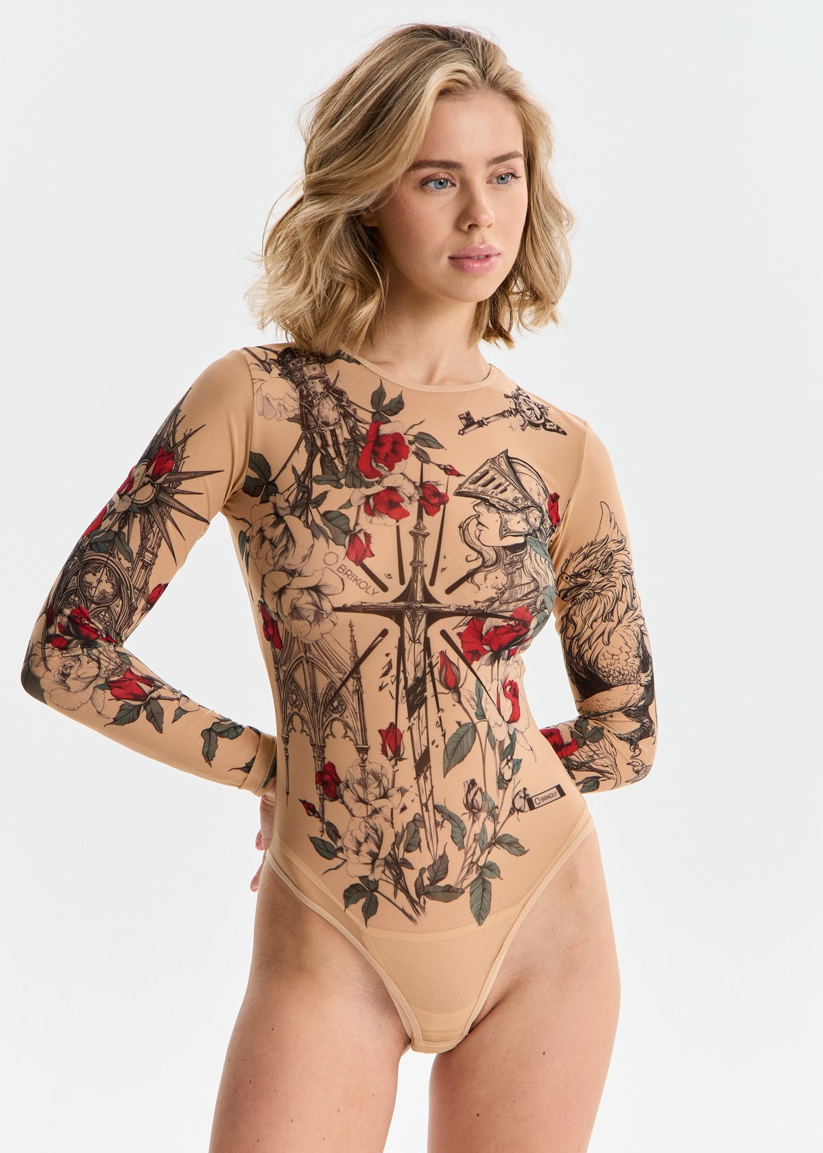 Woman wearing a beige bodysuit with black and red floral tattoo designs on a white background