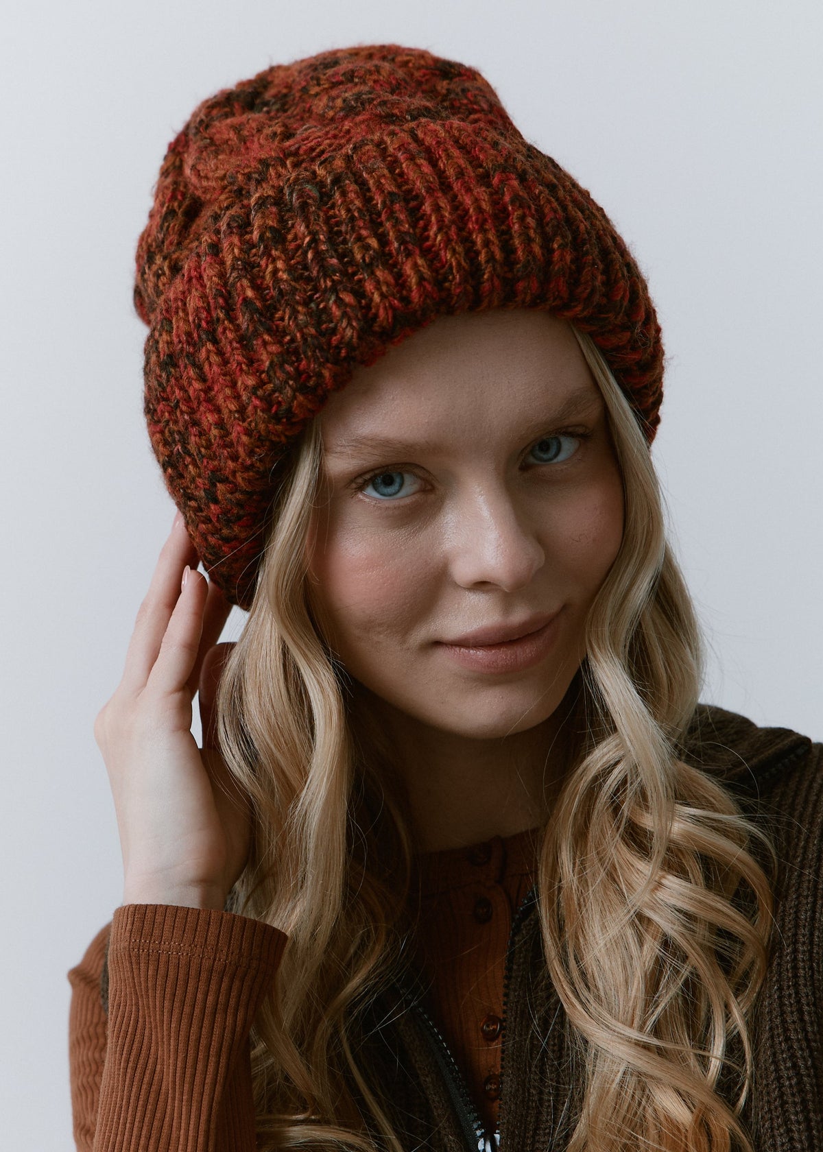 Tokyo Brown cable knit wool beanie: Front close-up with a hand beside the cuff