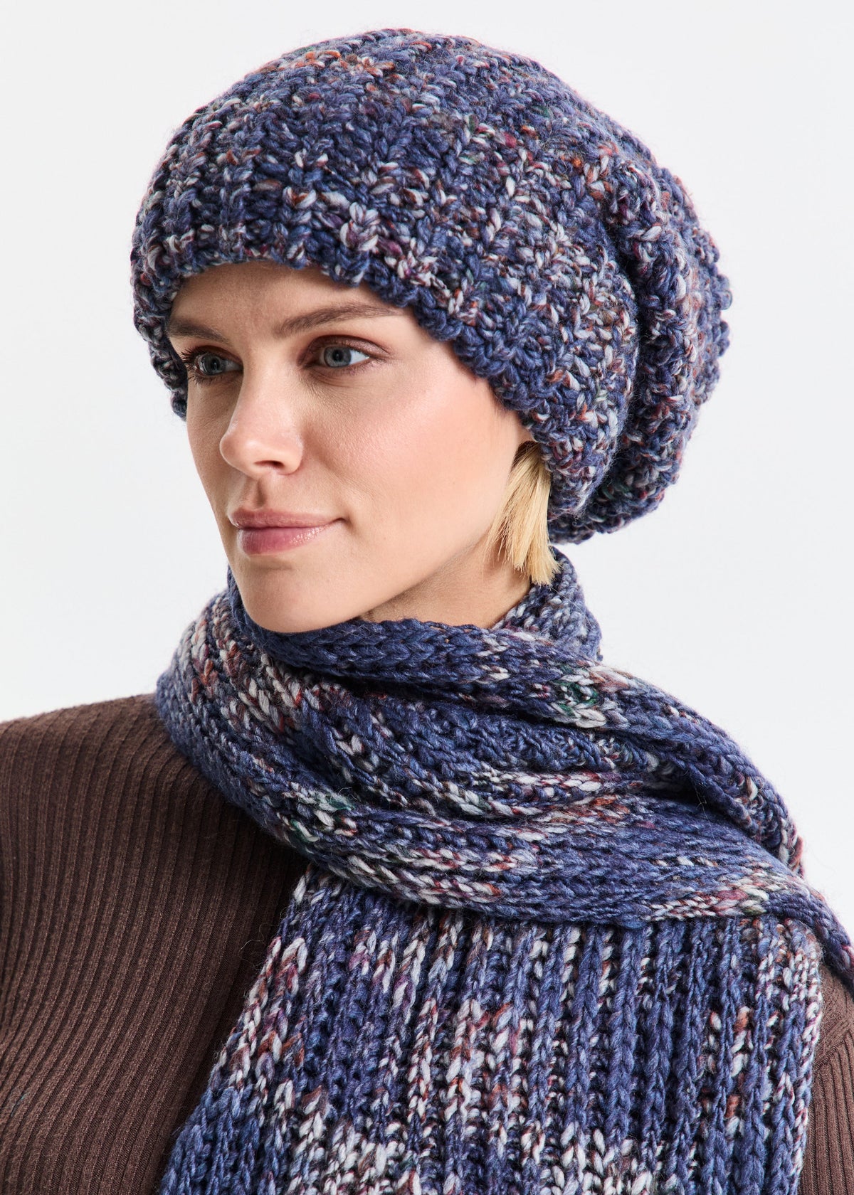 Woman wearing a blue knitted hat and scarf on a white background