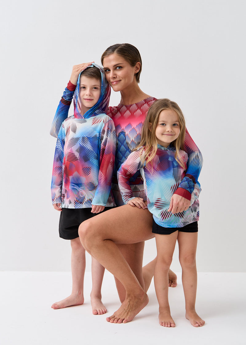 Woman and two children wearing matching colorful smart swimwear on a white background