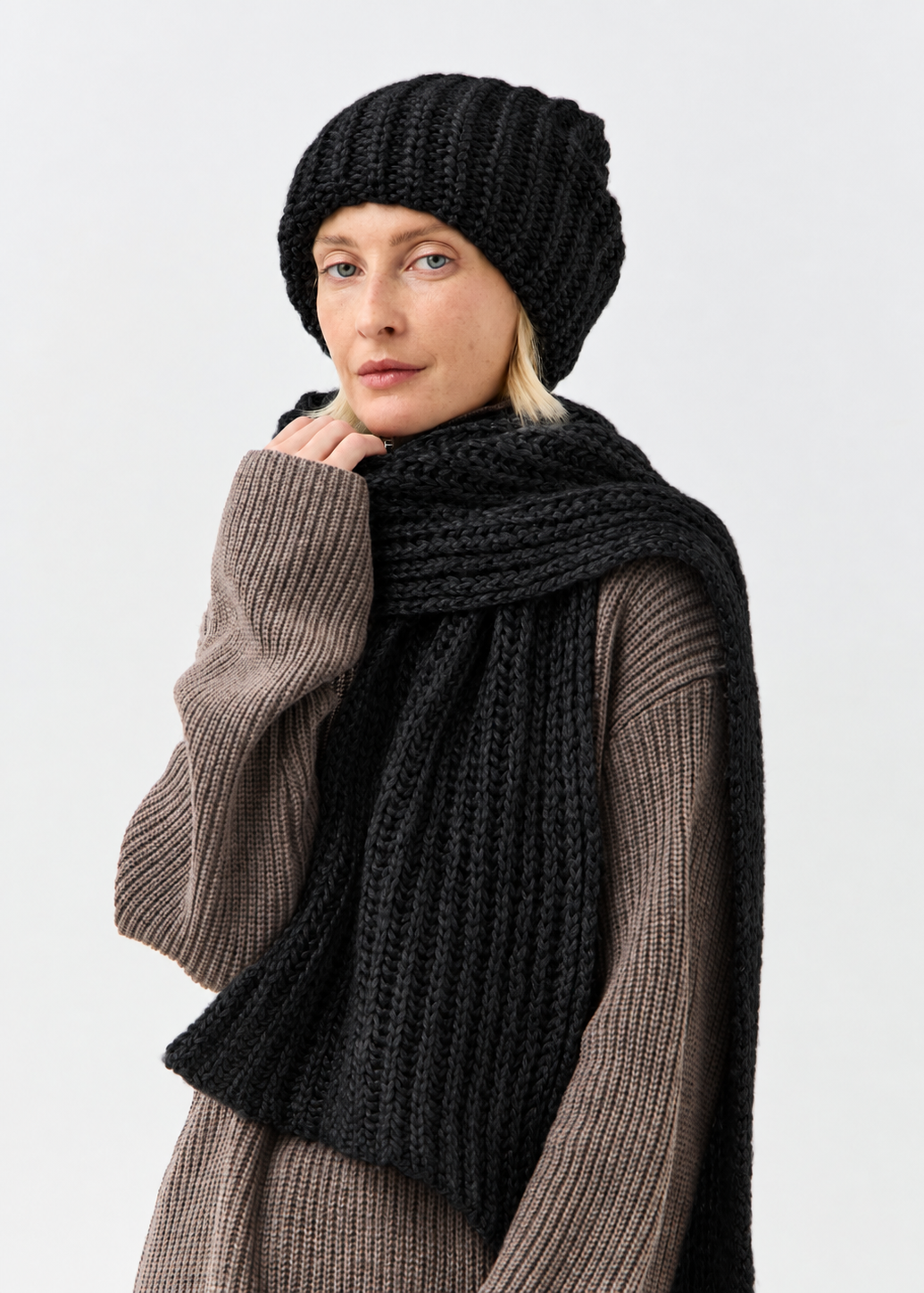 Lustre Black Melange alpaca-wool scarf: Three-quarter portrait with a hand beside the face; beanie sold separately