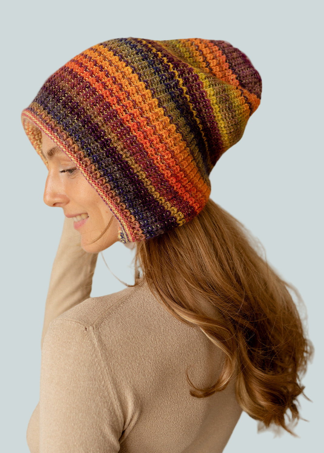 Woman wearing a colorful striped beanie against a plain background