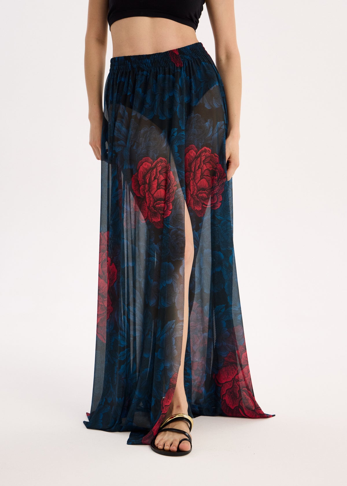 Long, dark blue skirt with red floral patterns worn by a person on a white background