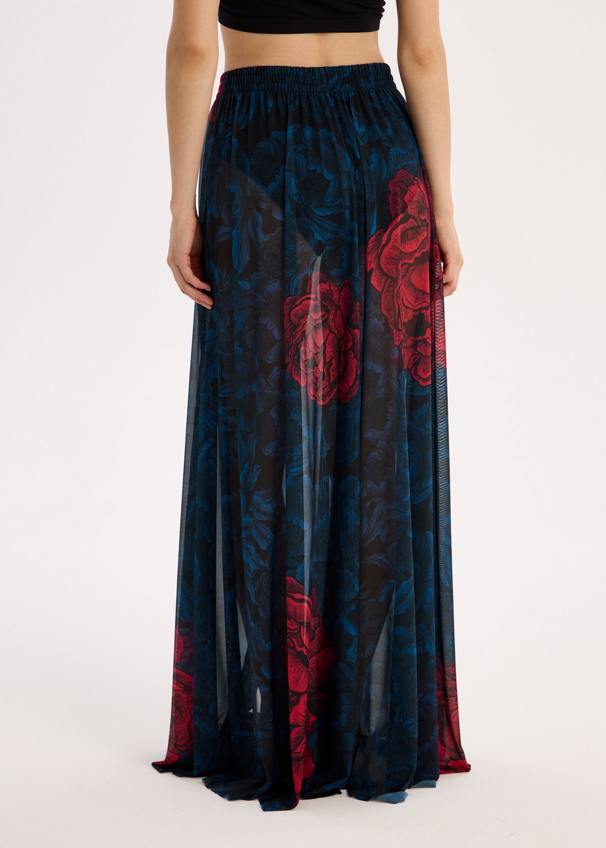 Long dark blue skirt with red floral patterns worn by a person on a white background