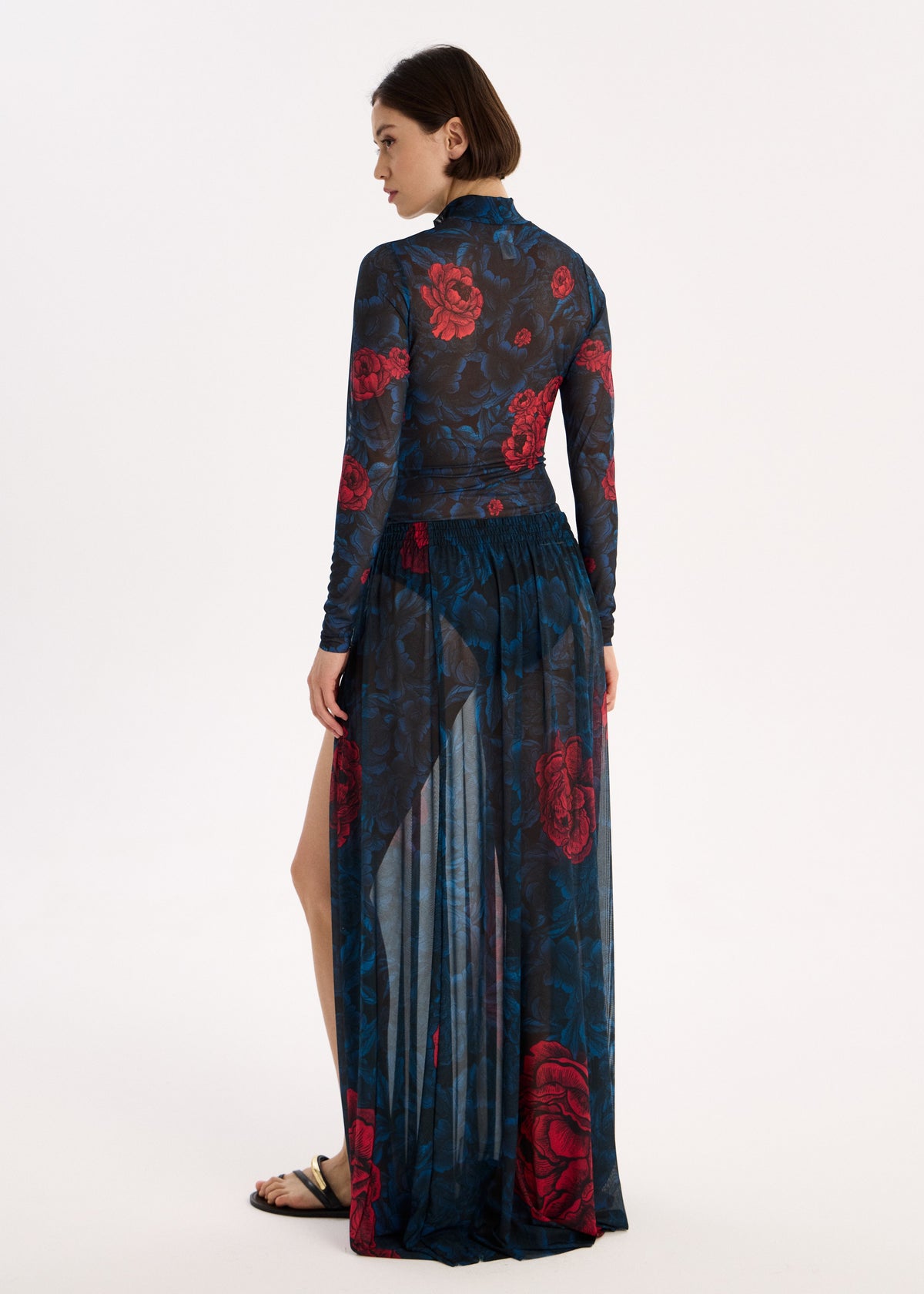 Woman wearing a long, dark blue skirt swimwear spf 50 with red floral patterns on a white background