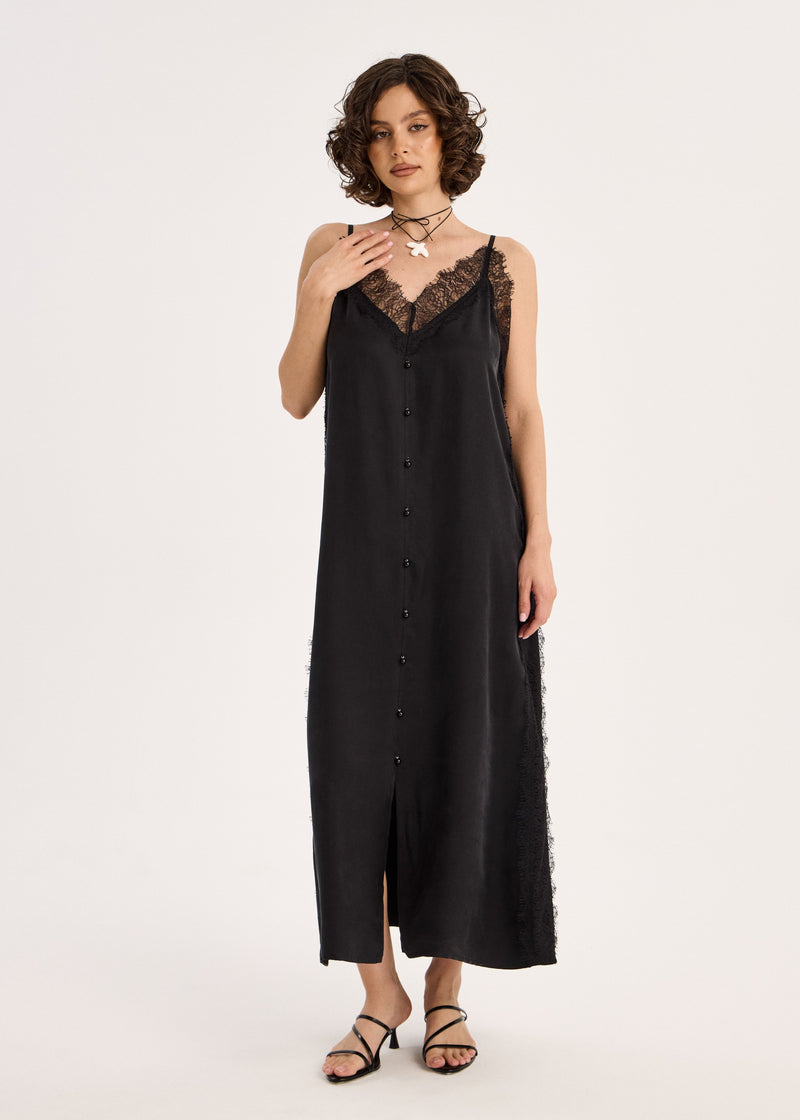 Woman wearing a black slip dress with lace details on a white background