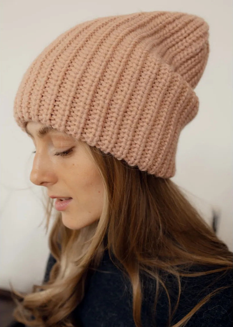 BRIKOLY London Peach knit beanie worn by a model looking down.